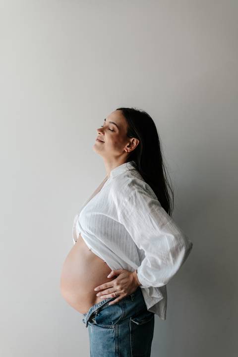 Gestante inclinada para trás aproveitando a iluminação natural.'