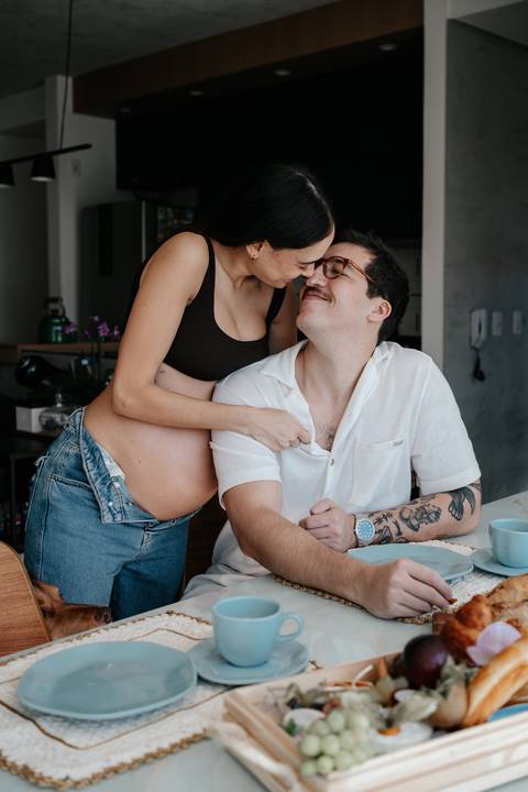 Casal trocando olhares e risadas sentados à mesa.'