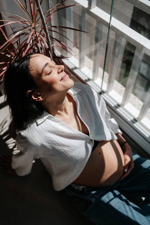 Gestante relaxada recebendo luz do sol no rosto.'