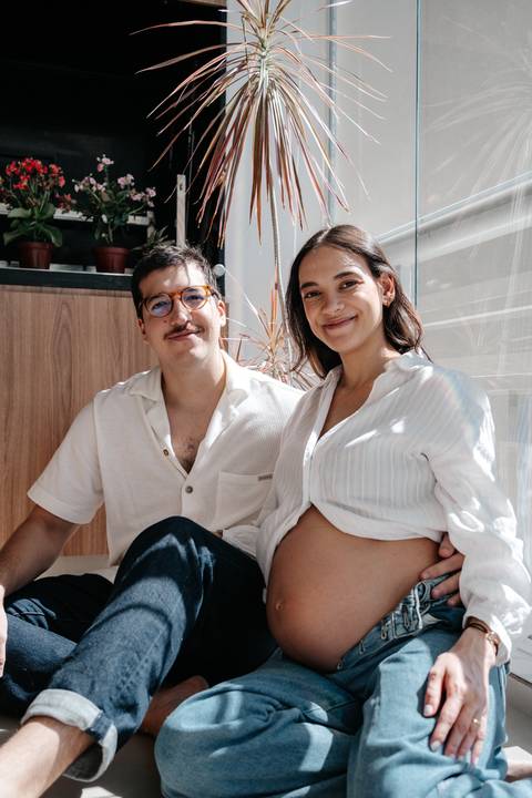 Casal sentado no chão sorrindo juntos para a câmera.'