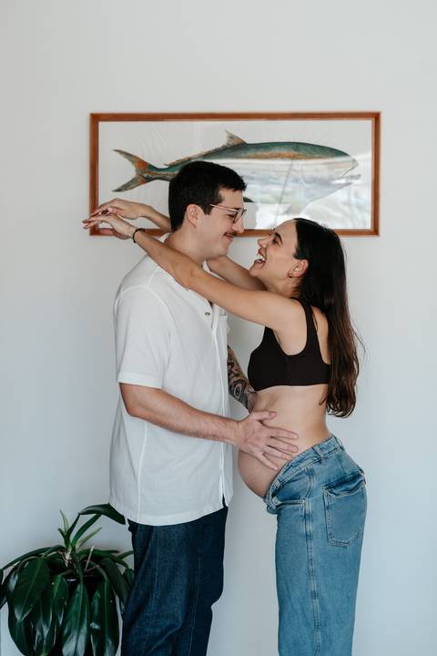 Casal trocando olhares e risadas descontraídas em pé.'