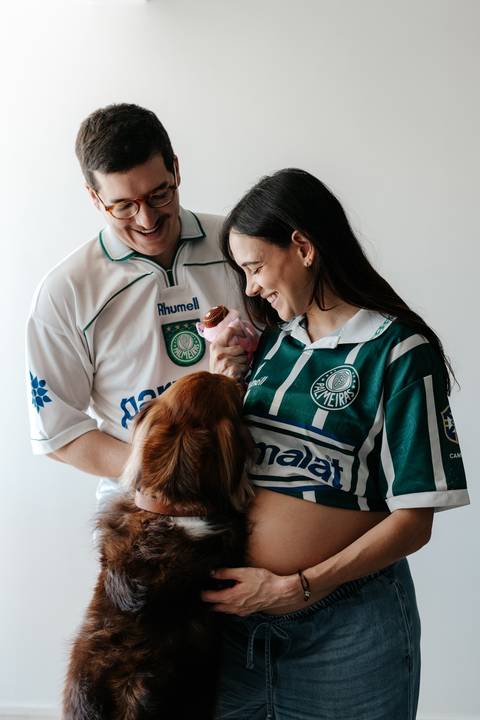 Casal e o cachorro interagindo com um ursinho rosa.'