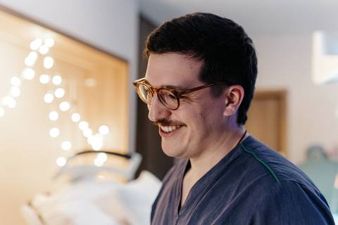 Retrato do pai sorrindo radiante na sala de parto iluminada.'