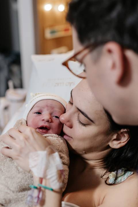 Mãe encostando o rosto e admirando o bebê de touquinha de perto.'