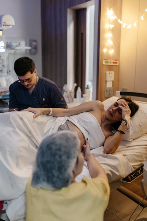 Gestante passando por contração com acompanhante ao lado.'