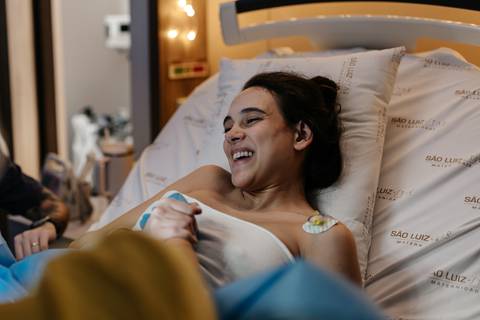 Gestante sorrindo aliviada e emocionalmente entregue no parto.'