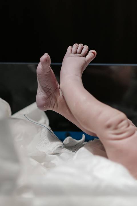 Detalhe das perninhas e pezinhos do bebê recém-nascido no berço.'