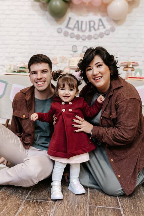 Retrato da família reunida sorrindo em frente à mesa decorada.'