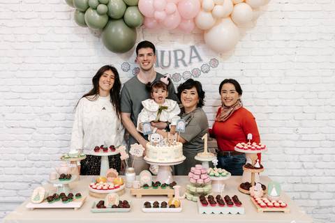 Foto em grupo com convidados e família reunidos na mesa principal.'