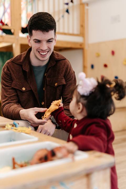 Pai entregando um brinquedo de plástico para a filha.'
