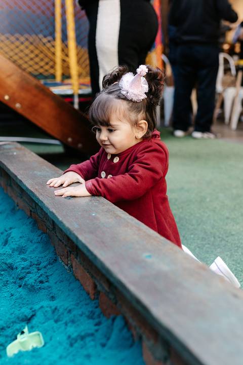 Aniversariante debruçada observando a piscina de bolinhas ou brinquedo.'