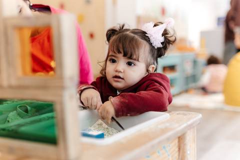 Aniversariante brincando na cozinha infantil de brinquedo.'
