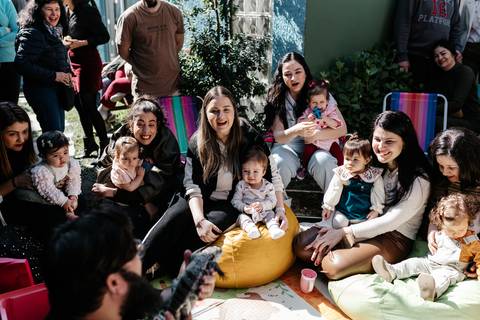 Crianças e famílias sentadas no chão assistindo à apresentação de animais.'