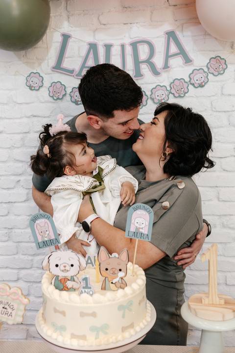 Retrato afetivo dos pais beijando as bochechas da aniversariante.'