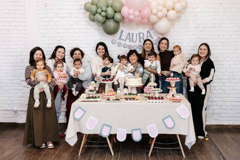 Foto geral com todas as mães e bebês convidados reunidos na mesa principal.'