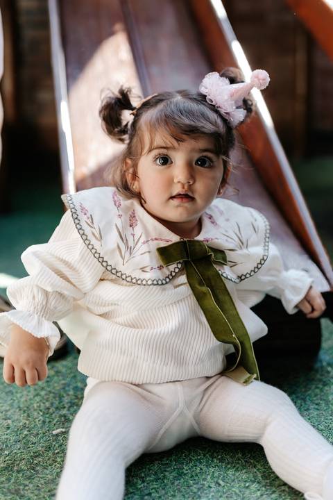 Retrato em close-up da aniversariante com roupa de laço verde.'