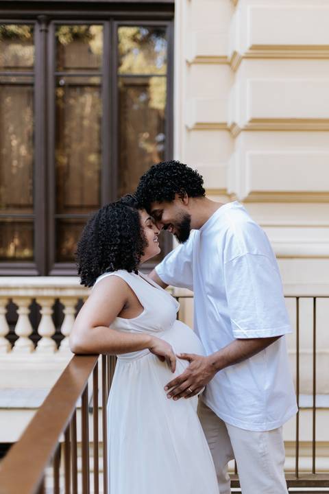 Casal encostando as testas com amor em frente à arquitetura clássica.'
