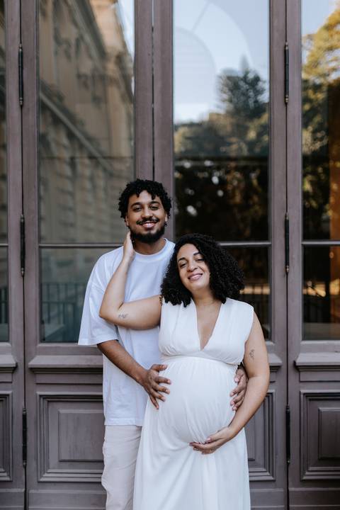 Casal sorrindo para a câmera com a mão da mãe no pescoço do parceiro.'