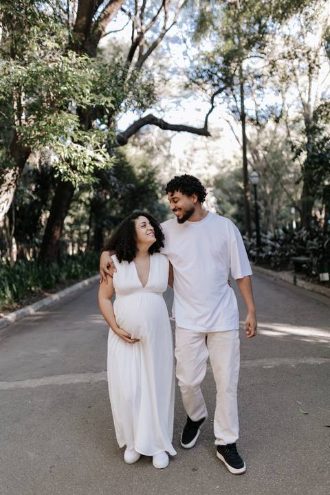 Casal sorrindo trocando olhares enquanto caminham ao ar livre.'