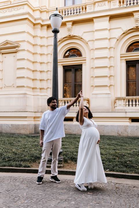 Casal dançando alegremente em frente ao prédio histórico.'