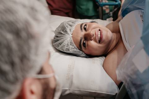 Mãe sorrindo de alívio e alegria ao olhar para o parceiro.'