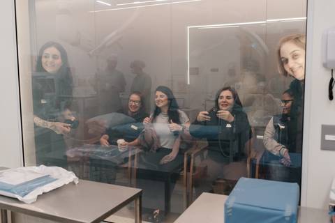 Família e amigos observando o parto através do vidro da sala de cirurgia.'