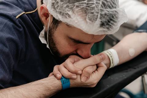 Pai beijando carinhosamente a mão da mãe durante o processo.'