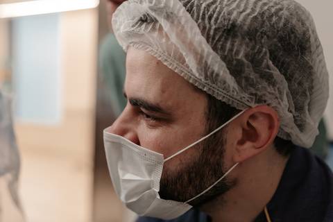 Retrato de perfil do pai de máscara e touca observando atencioso.'