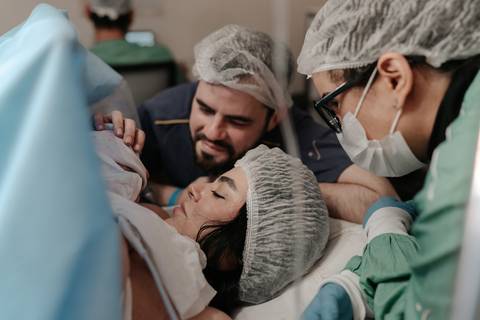 Pais e equipe médica reunidos celebrando a chegada do bebê.'