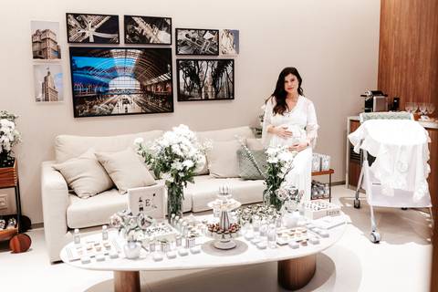 Visão geral do quarto de maternidade decorado em tons neutros e flores brancas.'