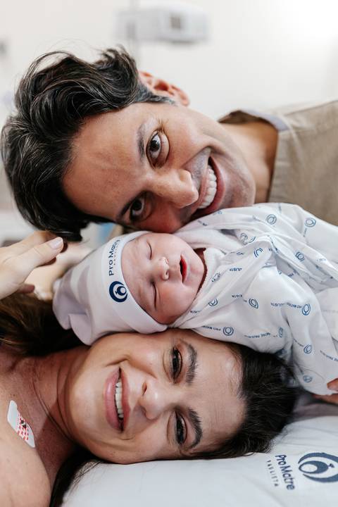 Família reunida trocando olhares e sorrisos na sala de nascimento.'