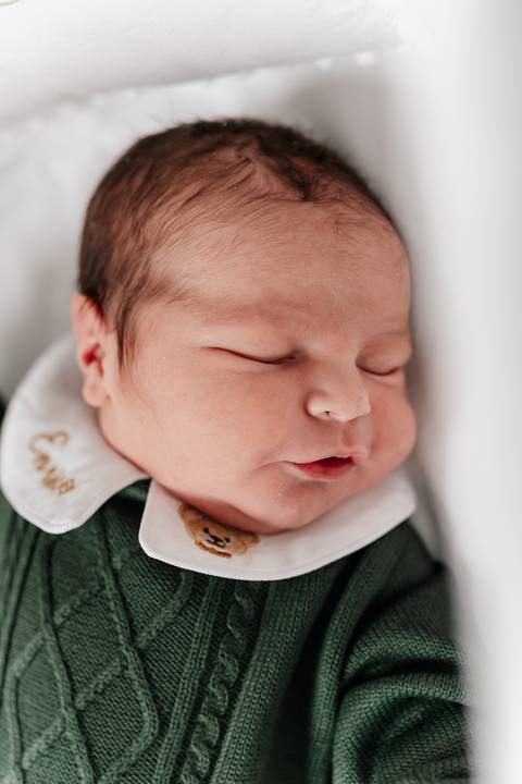 Retrato do bebê Enrico dormindo pacificamente com roupinha verde.'