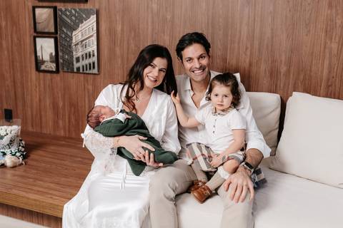 Retrato de família completo reunidos no sofá com os dois filhos.'