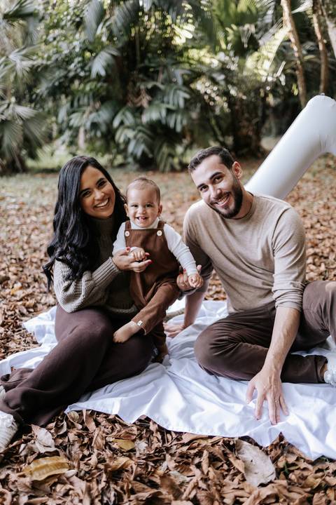 Gabriele e Matheus sorrindo ao lado de Rafael em ensaio de família'