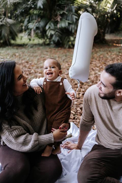 Gabriele e Matheus sorrindo ao lado de Rafael em ensaio de família'