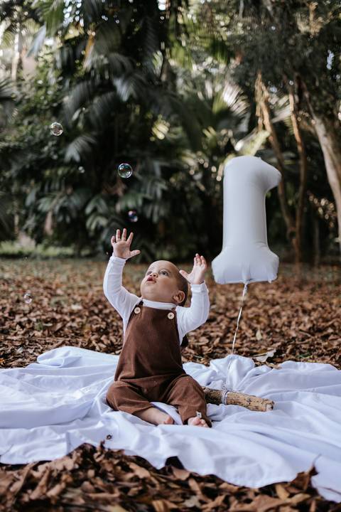 Rafael sorrindo e brincando com balão durante ensaio de 1 ano'