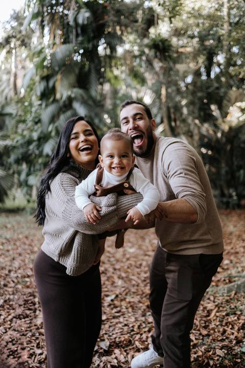Gabriele e Matheus sorrindo ao lado de Rafael em ensaio de família'