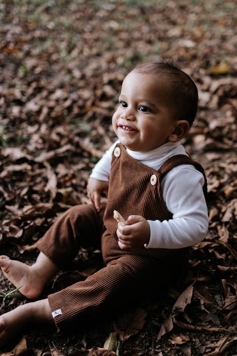 Rafael sorrindo sentado entre as folhas durante ensaio fotográfico de 1 ano  '