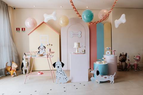 Decoração da festa de 1 ano da Olívia com tema cachorrinho, incluindo mesa do bolo, balões e elementos inspirados em cães.'