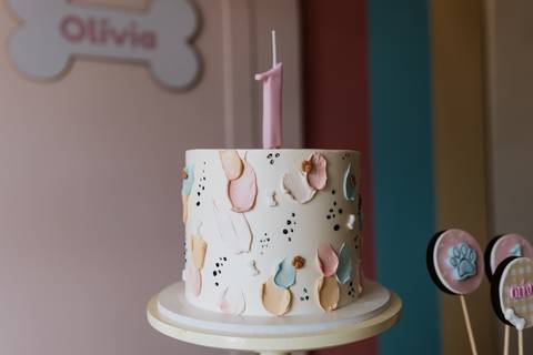 Bolo de aniversário de 1 ano da Olívia decorado com cachorrinhos, patinhas e detalhes coloridos.'