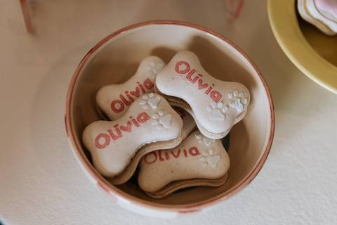 Docinhos personalizados com o nome Olívia em uma mesa decorada para a festa de 1 ano com tema cachorrinho.'