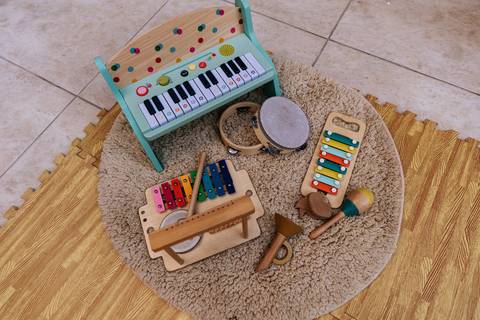 Brinquedos musicais e instrumentos infantis organizados em uma área de atividades da festa de 1 ano da Olívia.'