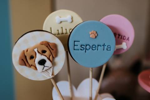 Doces personalizados com imagens de cachorrinhos e o nome Olívia decoram a festa de 1 ano com tema cachorrinho.'