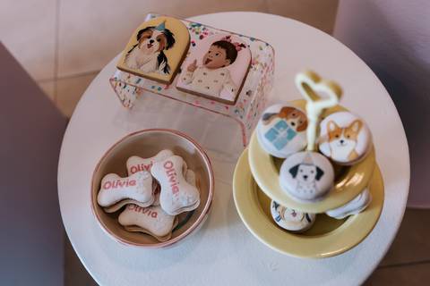 Mesa com doces e lembranças personalizadas da festa de 1 ano da Olívia, decorada com elementos de cachorrinhos.'