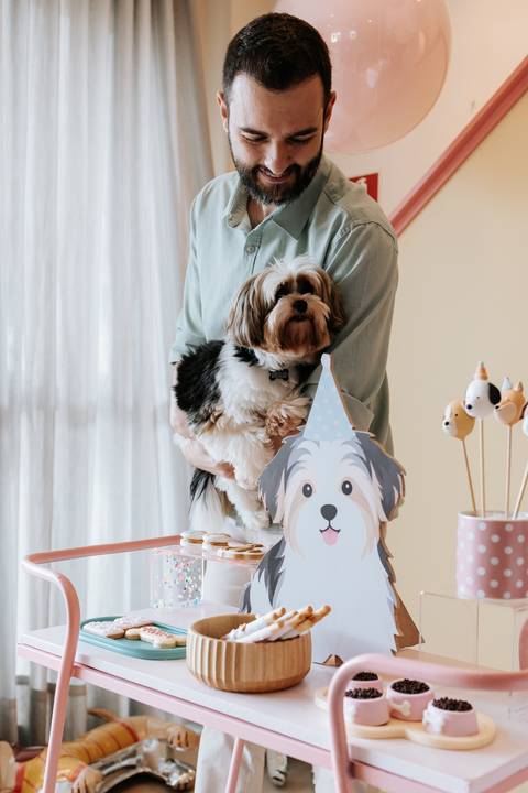 Cachorro da família ao lado da decoração da festa de 1 ano de Olívia, com elementos do tema cachorrinho ao fundo.'