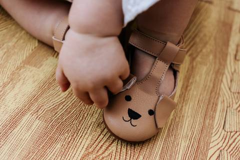 Detalhe dos pés de Olívia usando sapatinhos marrons com estampa de cachorrinho durante a festa de 1 ano.'