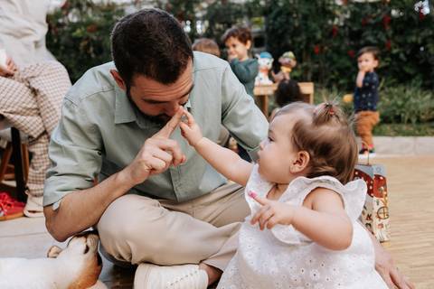 Olívia brincando ao lado do pai durante a festa de 1 ano, em um momento de interação e carinho entre os dois.'
