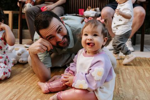 Olívia sorrindo ao lado do pai durante a festa de 1 ano.'