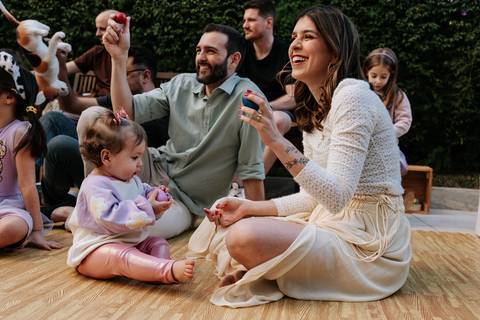 Olívia sentada entre os pais durante um momento de diversão em família.'