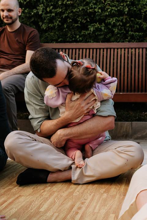 Pai abraçando e beijando Olívia durante a comemoração de seu primeiro aniversário'